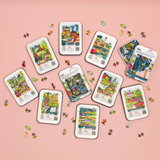 Collection of puzzle packaging on a pink background with scattered puzzle pieces.