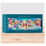 A teal puzzle box labeled ELEWHITE and WHISKEY TOWN, featuring a colorful winter village illustration on the front, photographed on a light wood surface against a pale gray background.