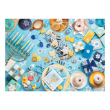 Hanukkah-themed table setting with menorah, dreidels, cookies, and candles on a blue background.