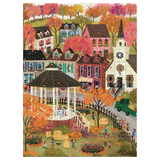 A completed jigsaw puzzle showing a colorful autumn village scene with houses, a church, a gazebo, trees in fall colors, and small people walking and playing in the foreground.
