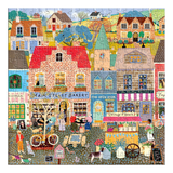A completed jigsaw puzzle featuring a colorful, whimsical village street scene with houses, shops, people, animals, bicycles, and flowers. The artwork is highly detailed with many small illustrated elements.