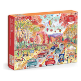 A 1000-piece jigsaw puzzle box by Pelican featuring a colorful autumn park scene with trees, cars, people, and hot air balloons. The box has an orange top and side, with a red spine panel and a printed preview of the puzzle design on the front.