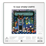 Square jigsaw puzzle packaging for 'Ye Olde Spooky Shoppe' by Galison, featuring a colorful illustrated storefront with a cat and Halloween-themed details, on a white background with product details printed below.