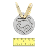 Gold and silver pendant with a measuring ruler for scale on a white background