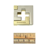 Gold and silver geometric puzzle with 'OHANAYAMA' branding, shown with a ruler for scale.