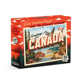 A 500-piece jigsaw puzzle box titled 'Greetings from Canada' by Main & Local. The box features a vintage-style Canadian postcard illustration with a bear, duck, maple syrup, and a red sky.