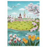 A completed jigsaw puzzle showing a colorful illustrated scene of a green hill with a large historic building, blue water, pink blossoms, tulips, and a boat under a blue sky.