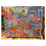 Colorful jigsaw puzzle box with illustrations of a cityscape on a wooden surface.