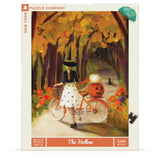 Puzzle box with a Halloween-themed illustration of a woman with a bicycle and pumpkin.