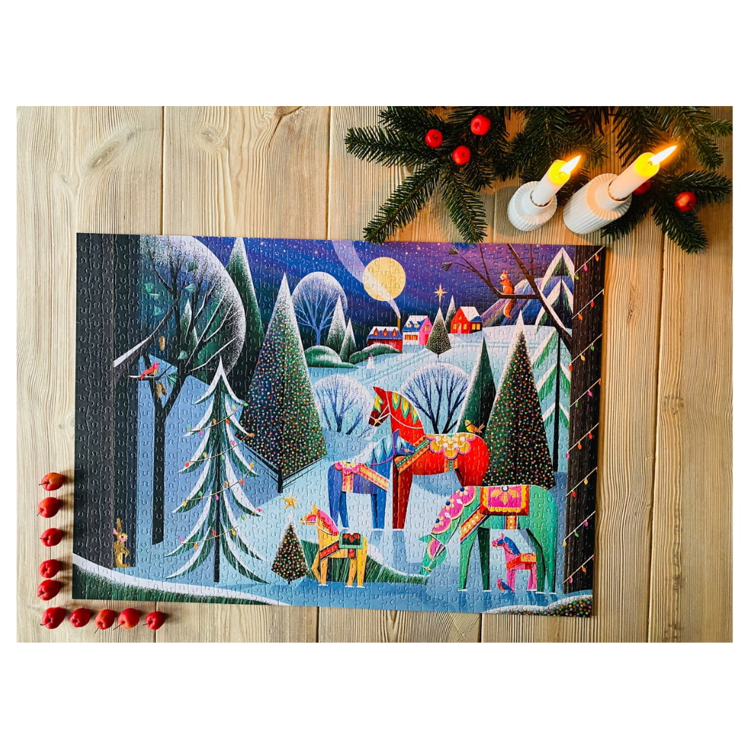 Decorative Christmas scene with Santa Claus and reindeer on a wooden surface with candles and greenery.