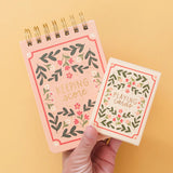 A card deck and score pad with floral designs and text on a yellow background