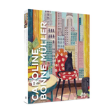 A jigsaw puzzle box 'Caroline Bonne Müller' featuring a colorful, whimsical illustration of a black cat sitting on a red floral chair against a city skyline background