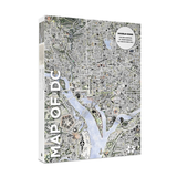 Ajigsaw puzzle titled "MAP OF DC" shown at a slight angle on a white background. The cover features a detailed grayscale city map with blue waterways and a white circular label reading "DOUBLE SIDED THE DECLARATION OF INDEPENDENCE ON THE REVERSE SIDE.
