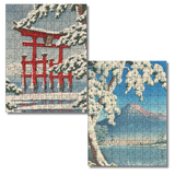 Two completed jigsaw puzzles showing winter landscapes: one with a red torii gate beneath snow-covered trees, and one with a mountain, snowy branches, and blue sky. The puzzles are displayed on a plain white background.