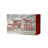 A rectangular jigsaw puzzle box featuring a winter Japanese-style illustration with snow-covered red temple buildings and torii gates, plus a solid red side panel with small white text.