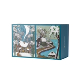 A rectangular jigsaw puzzle box with illustrated winter scenes on the front, shown against a plain white background. The box is teal-blue with snow-covered houses, trees, a winding path, and a small moon in the artwork.