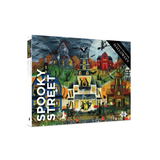 A jigsaw puzzle box titled 'Spooky Street Halloween' featuring a colorful, whimsical illustration of haunted houses, bats, and pumpkins on a dark street under a stormy sky.