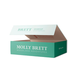 An open branded jigsaw puzzle box for Molly Brett Woodland Adventures, featuring a teal green exterior, white lettering, and a light interior, shown on a plain white background.