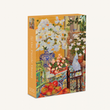 A 500-piece jigsaw puzzle box titled 'The Puzzle Theory' by artist Jørgel Matiléus. The box features a colorful still life painting of white flowers, red apples, and a blue patterned vase against a warm orange-yellow background.