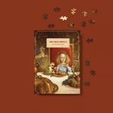 The Frog Prince 1000 Piece Puzzle shown as a completed book-style puzzle cover centered on a rust-brown background, with several loose puzzle pieces floating around it.