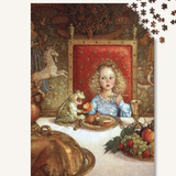 A jigsaw puzzle showing a whimsical medieval-style scene of a young girl in a blue gown seated at a table with a frog, fruit, and a red upholstered throne, with several loose puzzle pieces shown in the top-right corner on a white background.