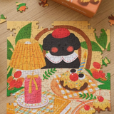 A colorful  jigsaw puzzle showing a whimsical cartoon scene with a black-and-white penguin, a yellow lamp, a pink candle, and a smiling character with a red nose, placed on a light wood surface with a few loose puzzle pieces around it.