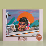 Puzzles of Color packaging with a woman in a car illustration on a green background