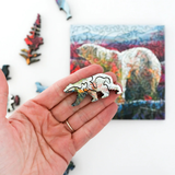 Hand holding bear-shaped puzzle pieces with a colorful bear illustration in the background