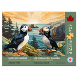 Jigsaw puzzle packaging featuring two puffins on a rocky shore with trees and water in the background.