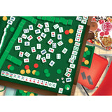 Mahjong game in progress on a green table with snacks and drinks in the background