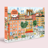 Jigsaw puzzle box with a colorful illustration of a New York street scene, featuring buildings and a mini market.