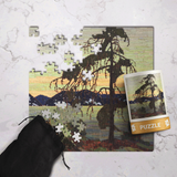 Jigsaw puzzle with a tree and mountain scene, partially completed, on a textured surface.