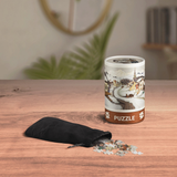 Puzzle packaging with scattered pieces on a wooden surface