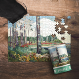Jigsaw puzzle with totem poles and nature scene on a wooden surface, accompanied by a completed puzzle and packaging.