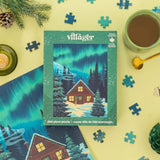 Villager puzzle box with Northern Lights design surrounded by puzzle pieces, a mug of coffee, and decorative items on a yellow background.