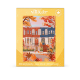 A 1000-piece jigsaw puzzle box by Villager Puzzles, featuring an illustration of colorful autumn townhouses framed by red and orange fall leaves. The packaging has a textured yellow border.