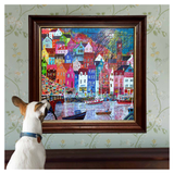 Dog looking at a colorful framed painting of a cityscape on a wall.