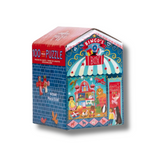 A 100-piece jigsaw puzzle box featuring a colorful illustrated fairground scene with a blue brick wall, red roof, striped awning, and cartoon characters. The box is photographed on a plain white background with a soft shadow.