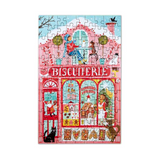 A completed colorful jigsaw puzzle featuring a whimsical pink and red bakery storefront with the word 'BISCUITERIE' across the front, surrounded by illustrated characters, animals, and decorative details on a white background.