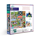A 1000-piece jigsaw puzzle box by Weebo, titled 'Country Fair'. The packaging features a colorful, whimsical illustration of a village fair with tents, people, and animals, along with product details and a small preview of the assembled puzzle piece design on a white background.