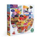 A 500-piece round jigsaw puzzle box by SeeYa featuring a colorful Mediterranean table scene with food, flowers, sailboats, and a bottle of water, shown on a white background.