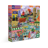 A 1000-piece jigsaw puzzle box featuring a colorful illustration of Paris in autumn, with landmarks, cyclists, a patisserie, and a river scene. The box is shown at a three-quarter angle on a plain white background.