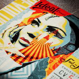 A close-up of a colorful printed poster or art print featuring a stylized illustrated face with bold graphic elements, including the words 'Ideal Power' and 'Sub J'.
