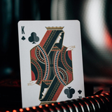 A single King of Clubs playing card stands upright against a dark, blurred background with red ambient light reflections.