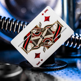 A custom-designed King of Hearts playing card with an intricate mechanical design, resting on a black stand against a dark, metallic background.