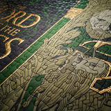 A close-up of a completed jigsaw puzzle featuring illustrated fantasy artwork in green, black, and metallic gold tones, with part of the text 'The Lord of the Rings.