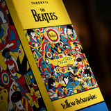 Close-up of a Theory 11 puzzke box of the Beatles 'Yellow Submarine'  jigsaw puzzle showing the iconic yellow background and dense multicolor illustrated artwork.